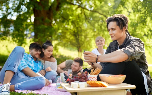 Man met smartphone op picnic met vrienden — Stockfoto