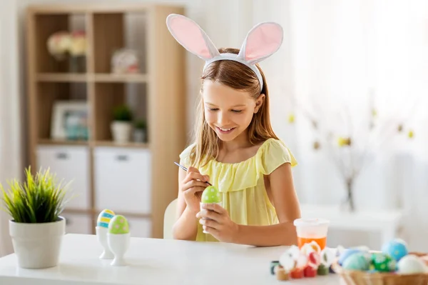 Happy girl coloring easter eggs at home — Stock Photo, Image