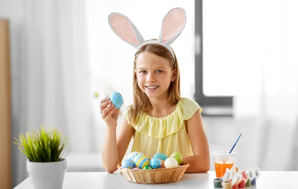 Menina feliz com ovos de páscoa coloridos em casa — Fotografia de Stock