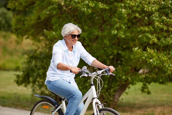 Gelukkig senior vrouw fietsten in zomer park — Stockfoto