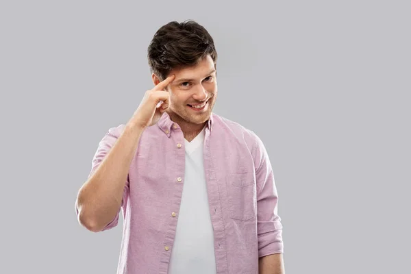 Sonriente joven apuntando con el dedo a su cabeza —  Fotos de Stock