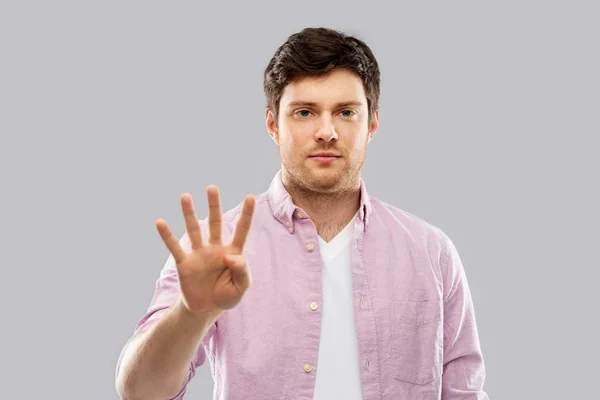 회색에 4 개의 손가락을 보여주는 젊은 남자 — 스톡 사진