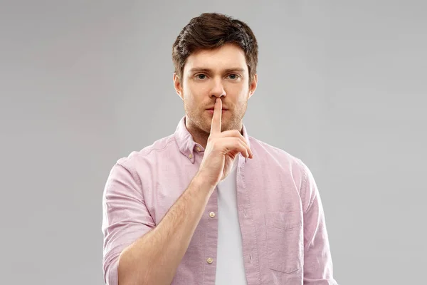 Молодой человек с пальцем на губах — стоковое фото