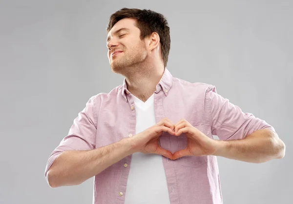 Hombre haciendo gesto del corazón de la mano sobre fondo gris —  Fotos de Stock