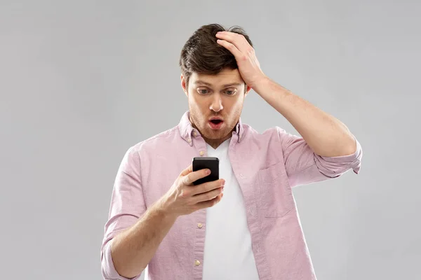 Смущенный молодой человек смотрит на смартфон — стоковое фото