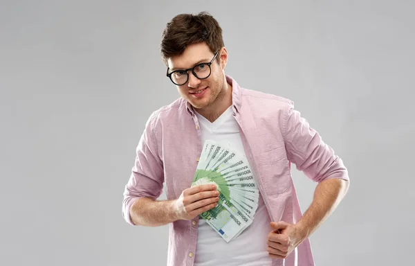 Šťastný mladý muž v brýlích s ventilátorem euro peníze — Stock fotografie