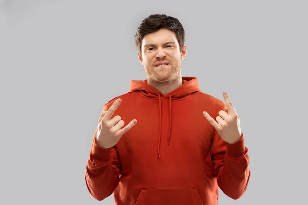 Young man in red hoodie showing rock sign — Stock Photo, Image
