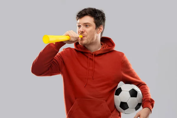Футбольный болельщик с футбольным мячом, дующий в рог — стоковое фото