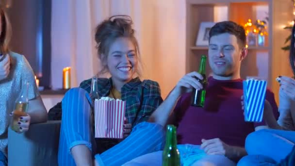 Друзья с пивом и попкорном смотрят телевизор дома — стоковое видео