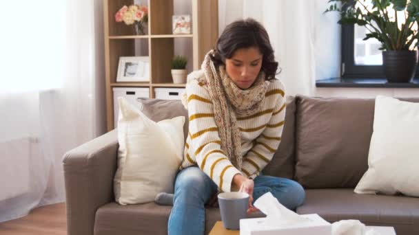 Sick young woman in scarf drinking hot tea at home — Stock Video