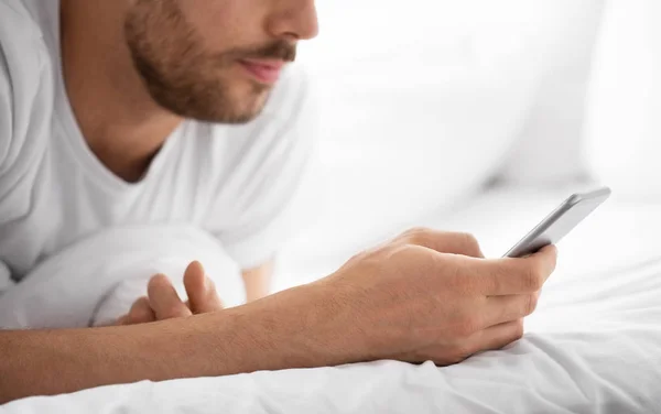 Nahaufnahme eines Mannes mit Smartphone morgens im Bett — Stockfoto