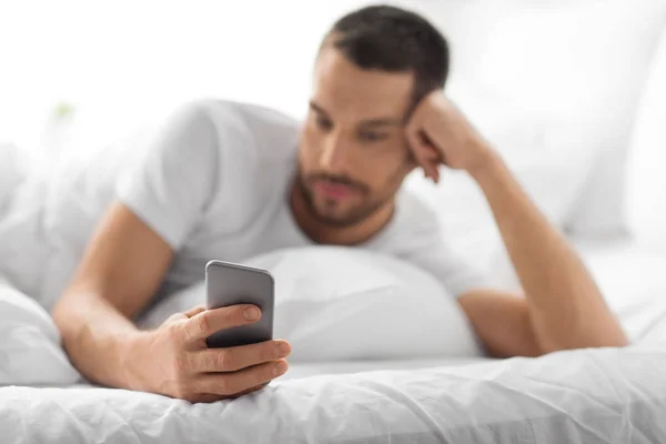 Primer plano del hombre con teléfono inteligente en la cama por la mañana — Foto de Stock