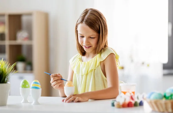 Menina feliz colorir ovos de Páscoa em casa — Fotografia de Stock