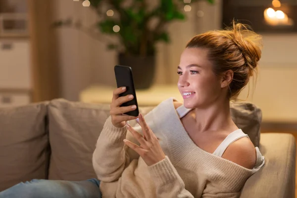 Jovem mulher feliz com smartphone em casa — Fotografia de Stock