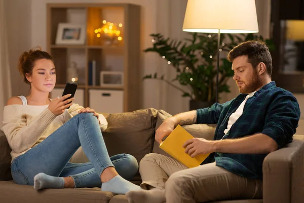 Couple with smartphone and book at home — Stock Photo, Image