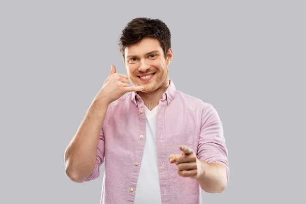 Glimlachend jongeman tonen telefoongesprek gebaar — Stockfoto