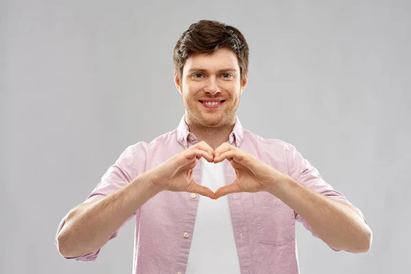 Mann macht Hand-Herz-Geste über Gey-Hintergrund — Stockfoto