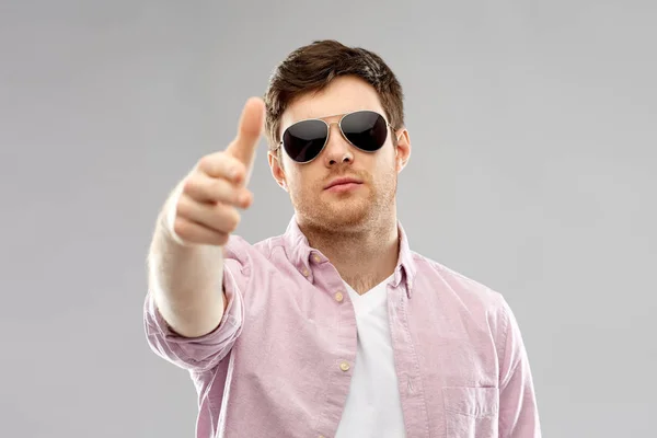 Jonge man in hand gun gebaar maken zonnebril — Stockfoto