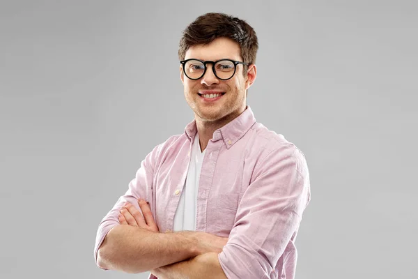 Leende ung man i glasögon över grå bakgrund — Stockfoto