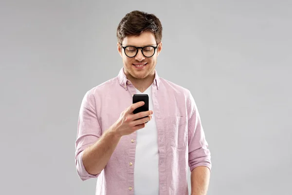 Jeune homme en lunettes regardant smartphone — Photo