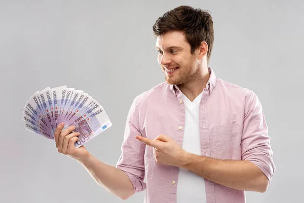 Jovem sorridente mostrando fã de dinheiro do euro — Fotografia de Stock