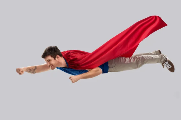 Человек в красном плаще супергероя, летящий в воздухе — стоковое фото