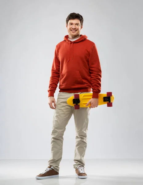 Sorrindo jovem com capuz com skate curto — Fotografia de Stock