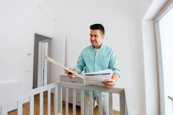 Padre con montaggio manuale lettino per bambini a casa — Foto Stock