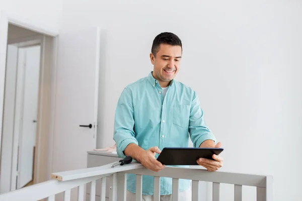 Padre con tablet pc assemblaggio lettino per bambini a casa — Foto Stock