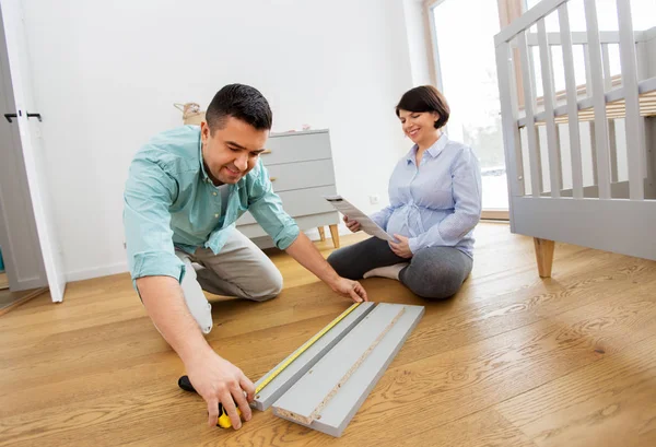 Familienpaar baut Babybett zu Hause zusammen — Stockfoto