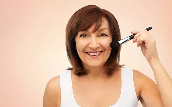 Lachende senior vrouw met make-up bloost borstel — Stockfoto
