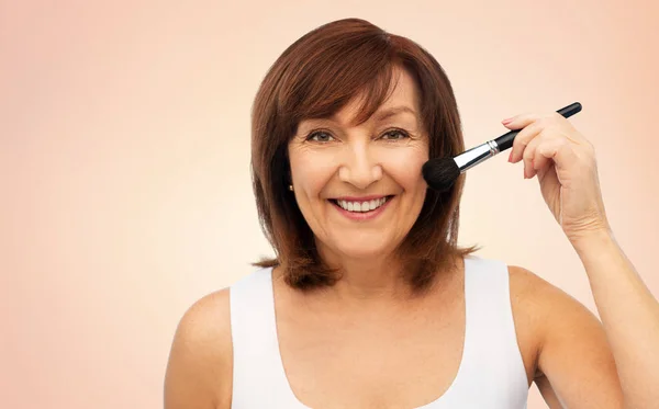 Femme âgée souriante avec brosse à blush maquillage — Photo