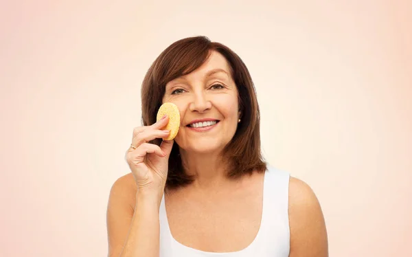 Woman cleaning face with exfoliating sponge — Stock Photo, Image