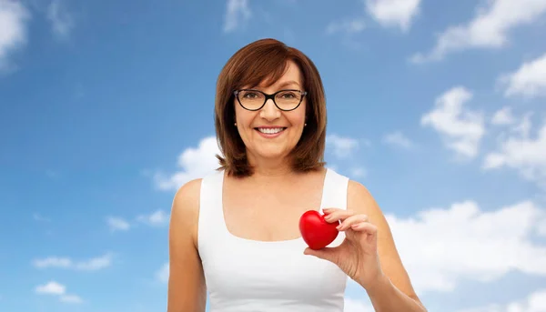 Retrato de mujer mayor sonriente sosteniendo el corazón rojo —  Fotos de Stock