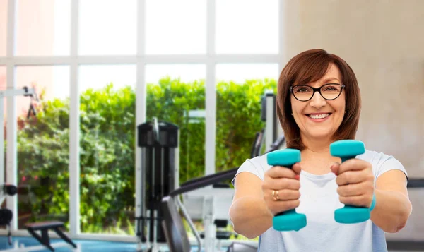 Sonriente mujer mayor con mancuernas haciendo ejercicio —  Fotos de Stock