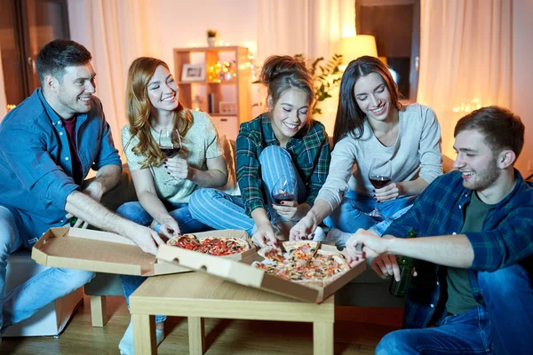 Amigos comiendo pizza y bebiendo vino tinto en casa — Foto de Stock