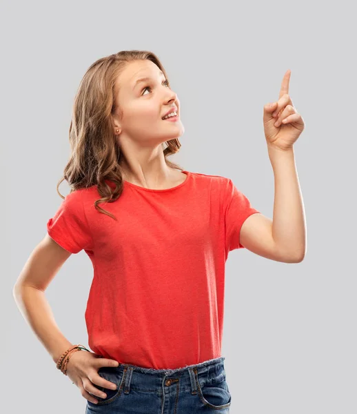 Smiling teenage girl pointing finger to something — Stock Photo, Image