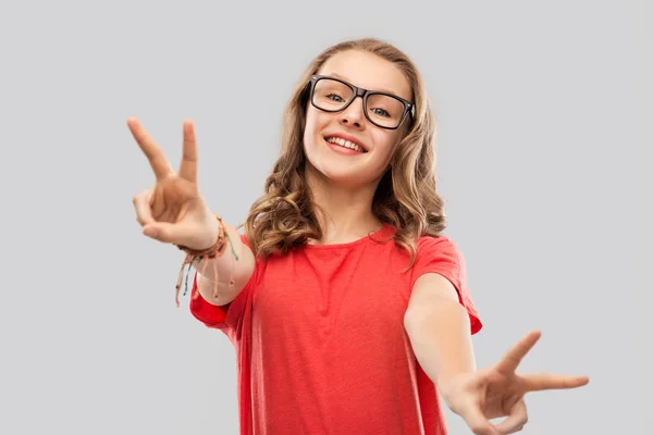 Smiling student girl in glasses showing peace — Stock Photo, Image