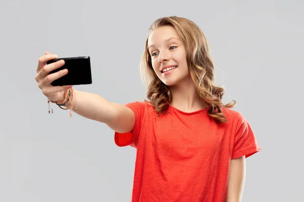 Smiling teenage girl taking selfie by smartphone — Stock Photo, Image