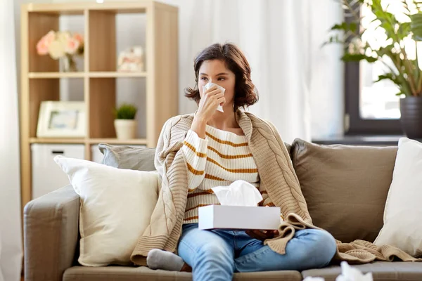 Sick woman blowing nose in paper tissue at home — Stock Photo, Image