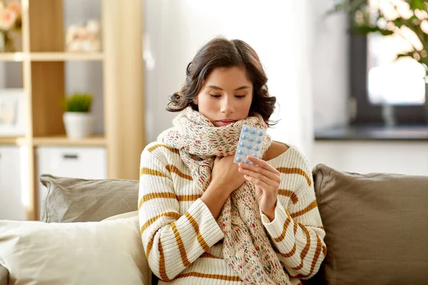 Sjuk kvinna i halsduk med medicin piller hemma — Stockfoto