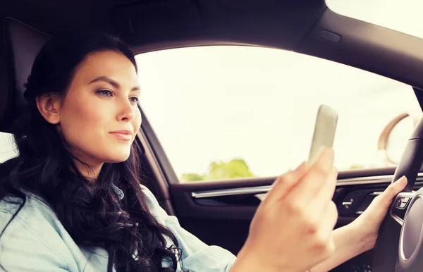 Счастливая женщина за рулем автомобиля со смартфоном — стоковое фото