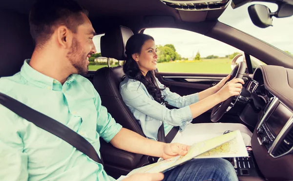 Homem e mulher felizes com mapa da estrada dirigindo no carro — Fotografia de Stock