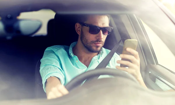 Homem em óculos de sol carro de condução com smartphone — Fotografia de Stock