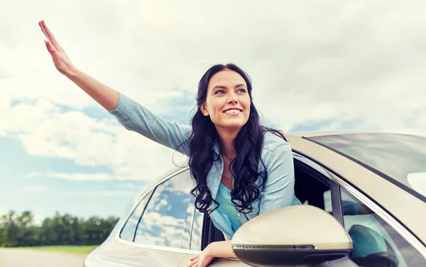 Feliz jovem mulher dirigindo no carro e acenando mão — Fotografia de Stock