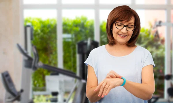 Mujer mayor sonriente con rastreador de fitness en el gimnasio —  Fotos de Stock