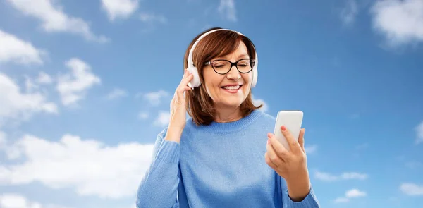 Mujer mayor en auriculares escuchando música en la celda —  Fotos de Stock
