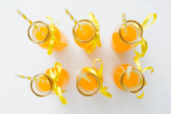 Orange juice in glass bottles with paper straws — Stock Photo, Image