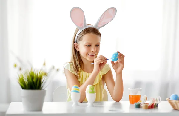 Happy girl coloring easter eggs at home — Stock Photo, Image