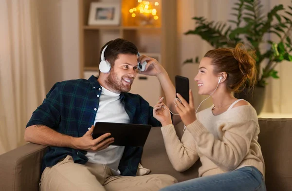 couple with gadgets listening to music at home